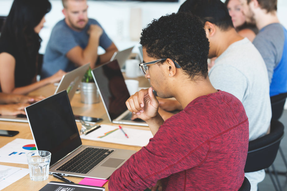 Diverse tech team collaborating with laptops in modern office